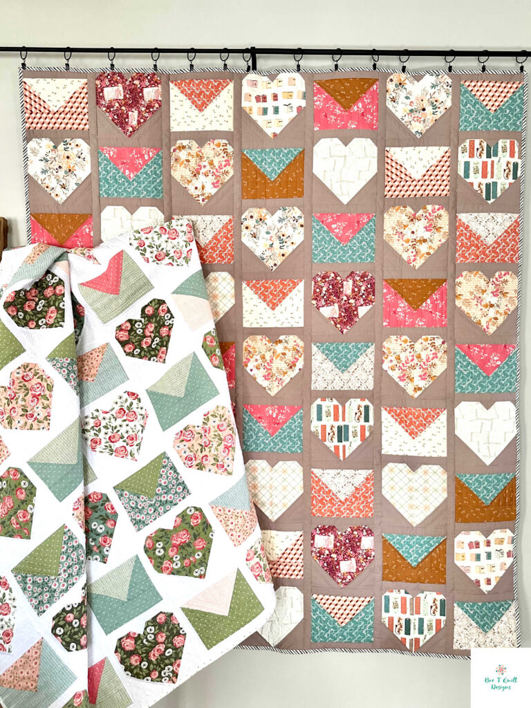 The Love Letters quilt hanging from a wall, showcasing the warm cider and dusty rose palette of the Bookish fabric collection.