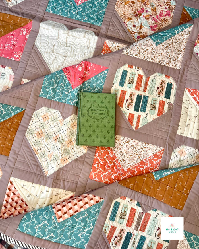 A literary themed quilt laid out with a book, emphasizing the cozy reading-room aesthetic.