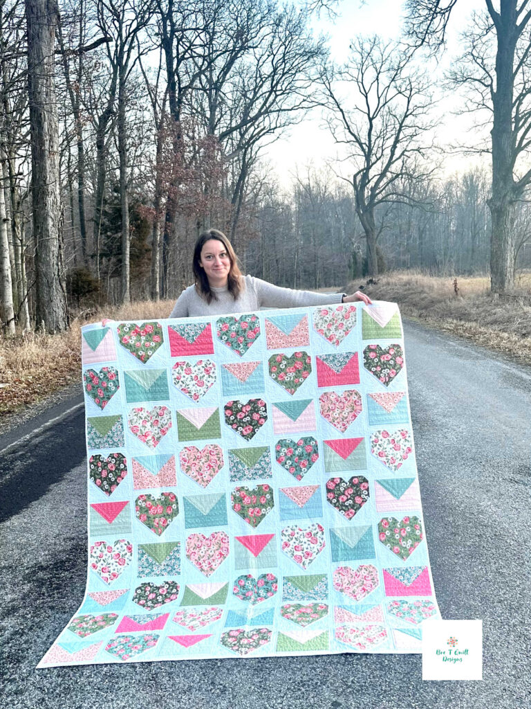 The Love Letters Valentine quilt pattern displayed by Bre outdoors, showing the full 62 by 72 inch throw size.