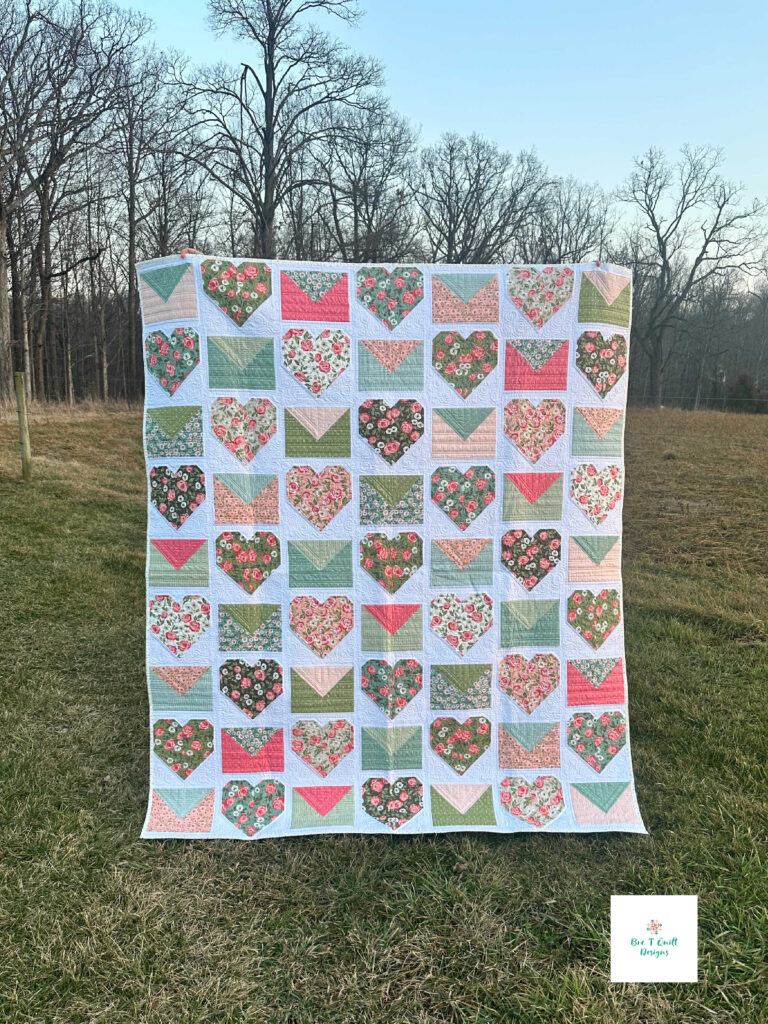 The Love Letters Valentine quilt pattern displayed outdoors, showing the full 62 by 72 inch throw size.