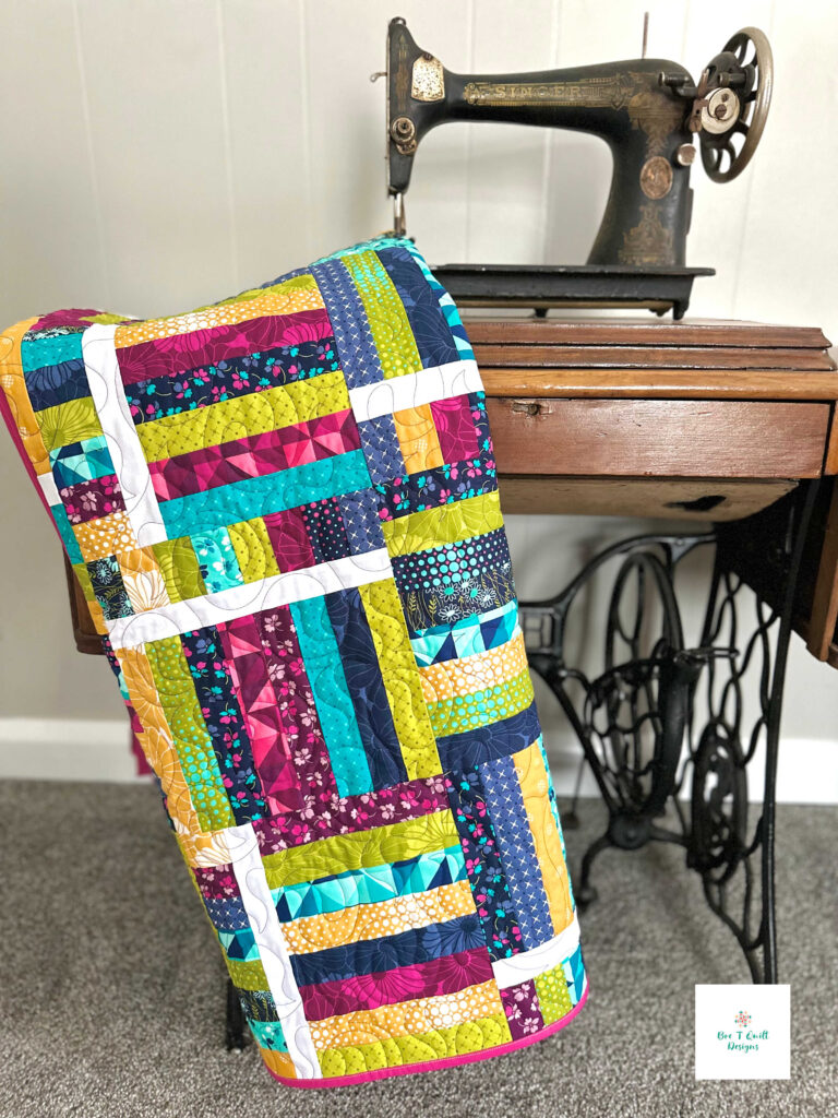 Switchback Rails Quilt Pattern- Bre T Quilt Designs Switchback rails quilt pattern, a modern twist on a fence rails quilt pattern, hanging over a vintage sewing machine table.