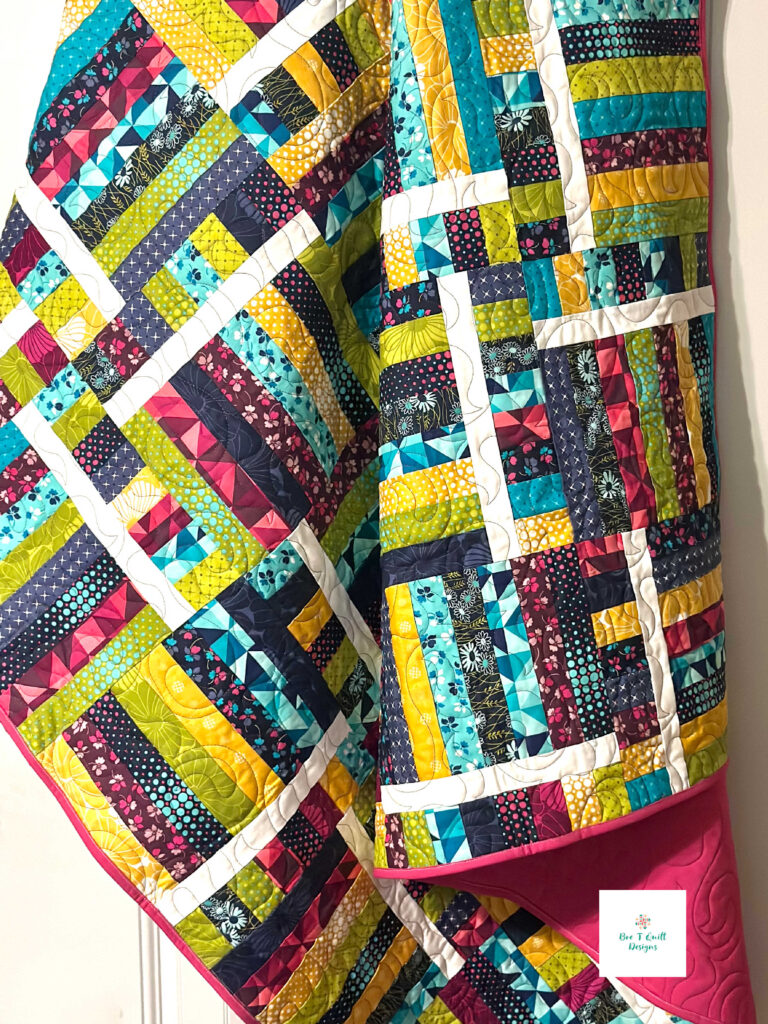 Switchback Rails Quilt Pattern- Color Crush- Bre T Quilt Designs Colorful quilt hanging over door frame featuring a fence rail quilt pattern.