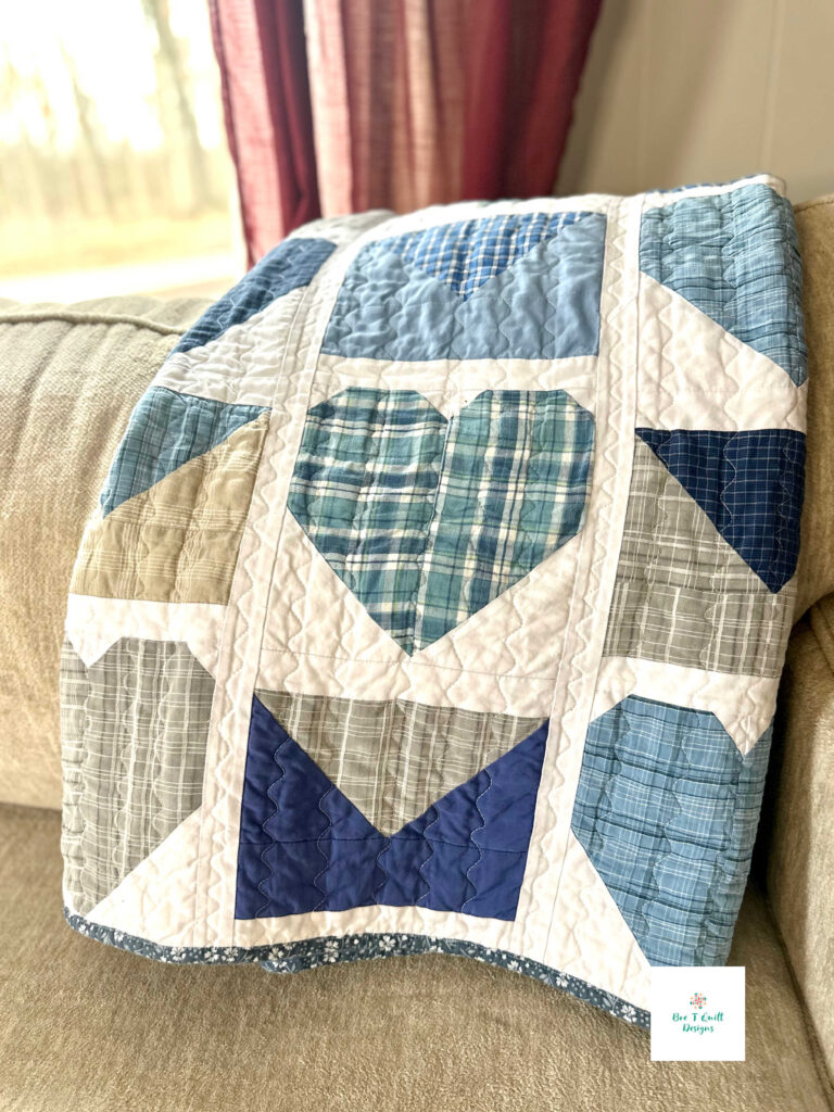 Love Letters Memory Quilt- Bre T Quilt Designs The Love Letters heart memory quilt draped over the back of a neutral-colored couch, styled as a cozy home heirloom ready for cuddling.