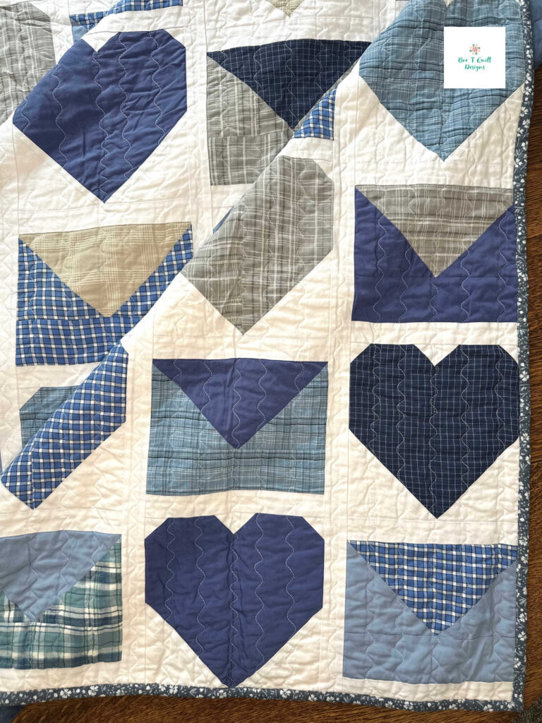 Detailed view of the wavy stitch quilting done on a Janome MC6650, showing the organic texture over a heart block made from a blue plaid shirt.