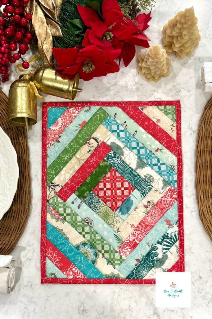 Quilted casserole hot pad in Winter Haven fabric by Rachel Rossi for Benartex, displayed on a Christmas table with white plates, golden bells, red florals, and beeswax Christmas tree candles