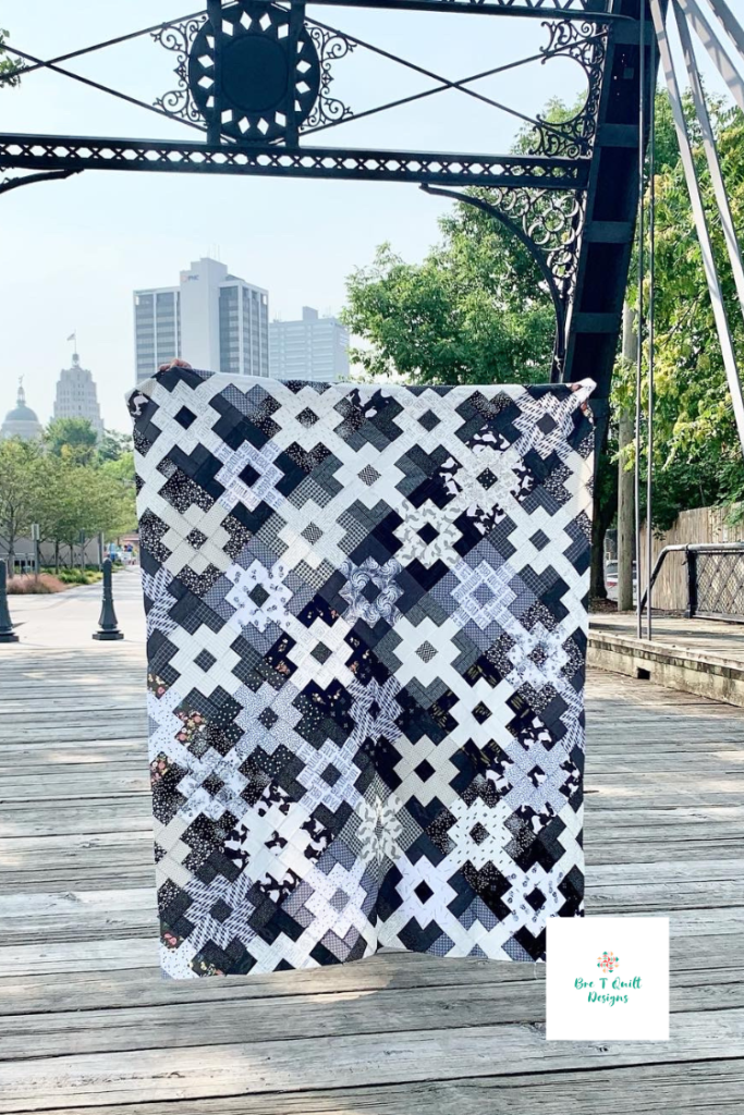 black and white scrap quilt pattern, full quilt top featured on a bridge. 