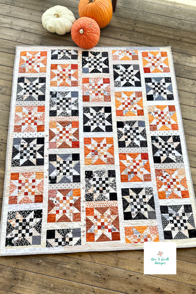Star quilt pattern made with orange and black scrap fabrics in a diagonal design. Full view.