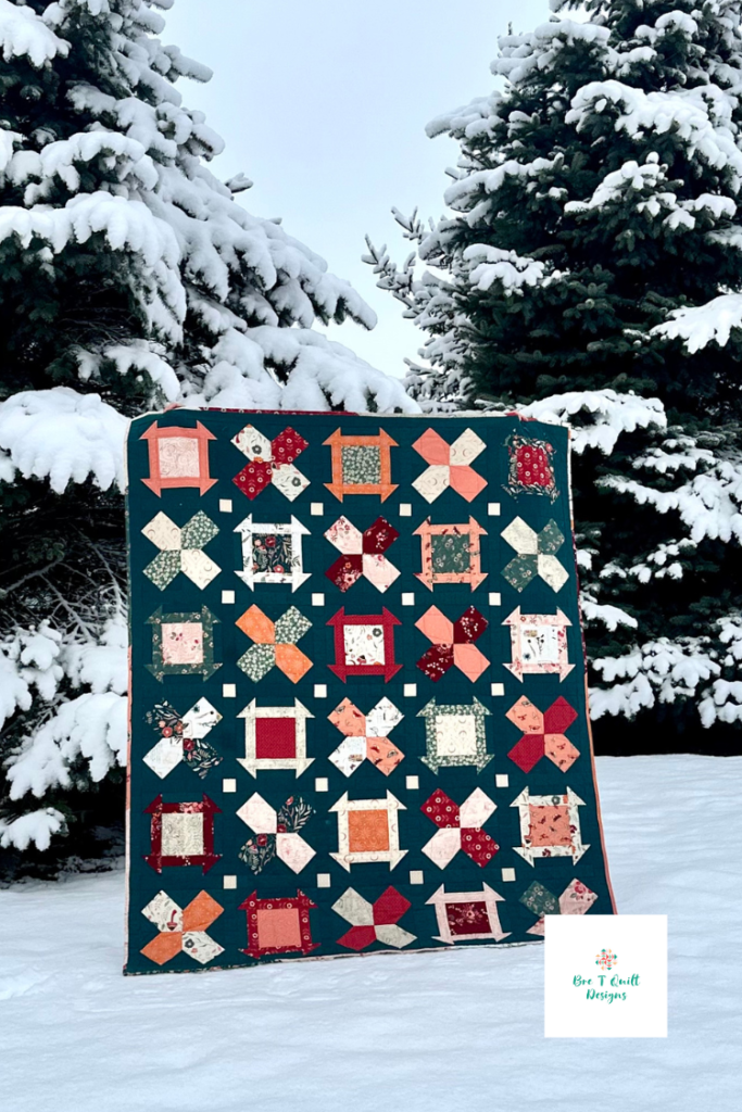 Teal, orange and red heirloom quilt photographed outside in the snow. 
