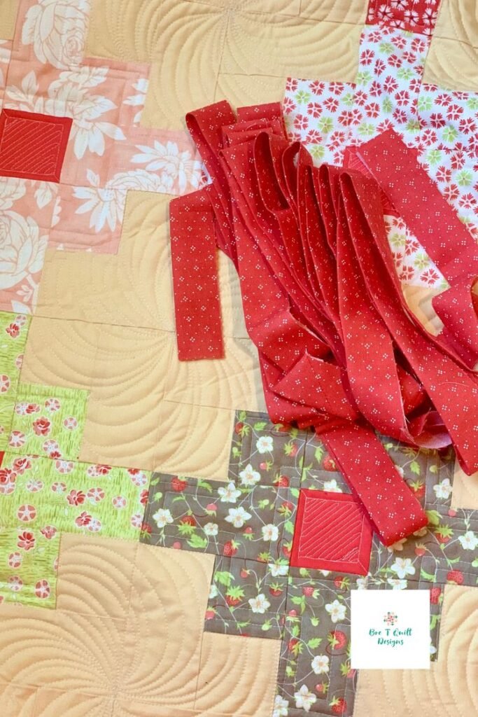 close up of yellow quilt with pinks and green fabric. with coral pink binding. 