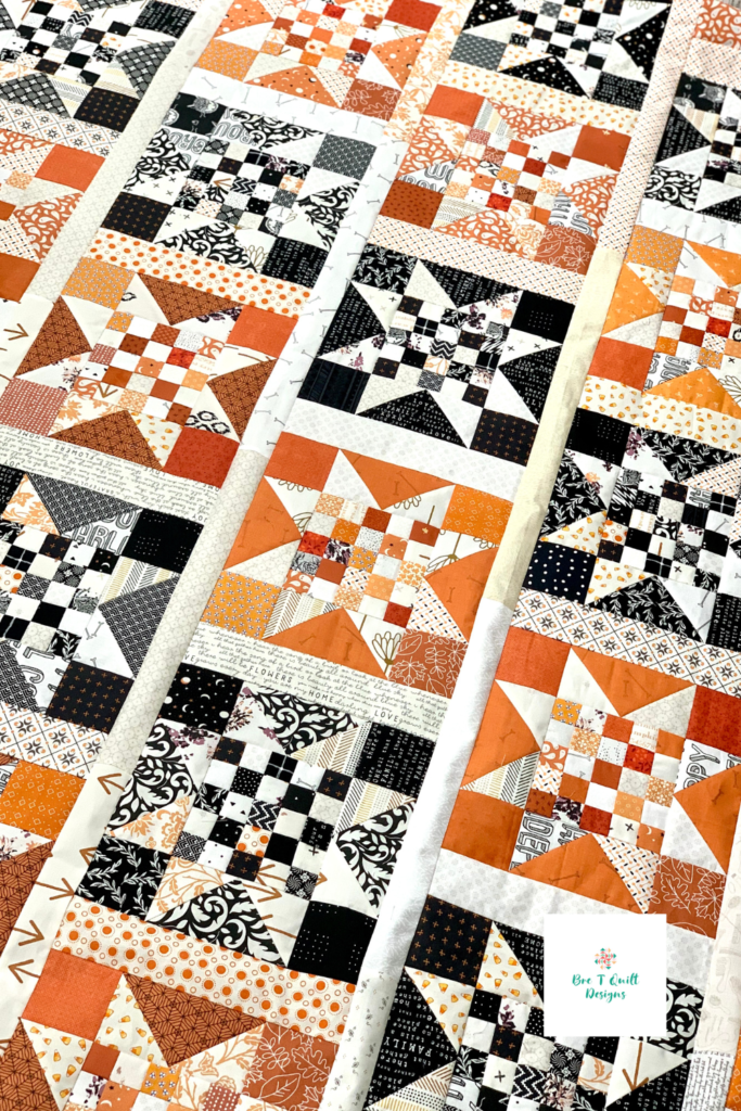 orange and black scrappy quilt top featuring checkered star pattern.
