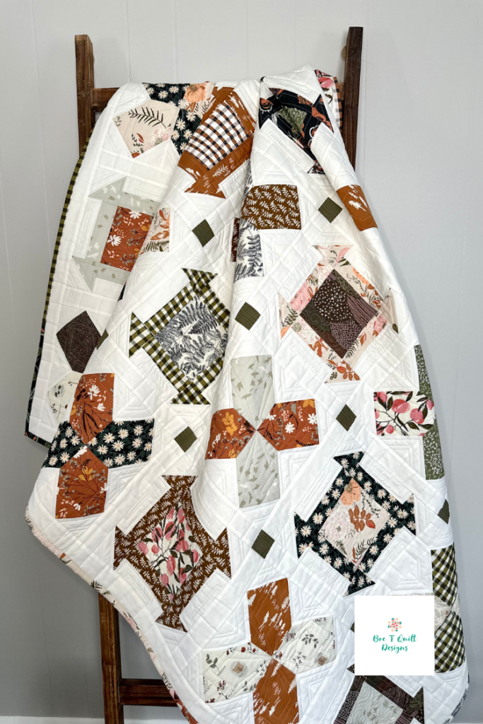 Mayflower and Churn dash quilt pattern in earthy fabrics hanging on a quilt ladder. 