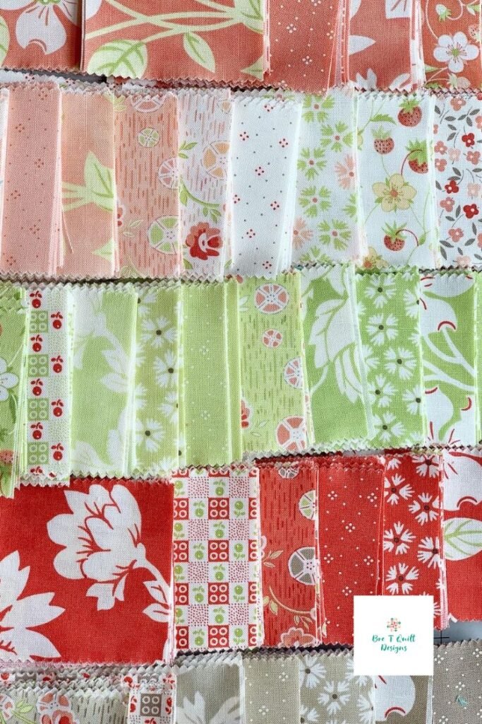 cut up pieces of jelly roll strips of strawberry and rhubarb fabric. 