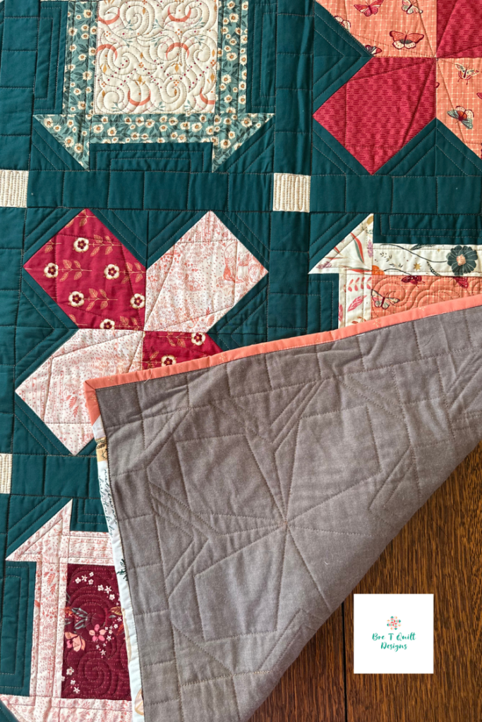 Close up of teal quilt with red and orange blocks, woven brown background fabric. 