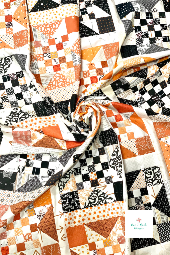 quilt swirl of orange and black scrappy quilt top featuring checkered star pattern.