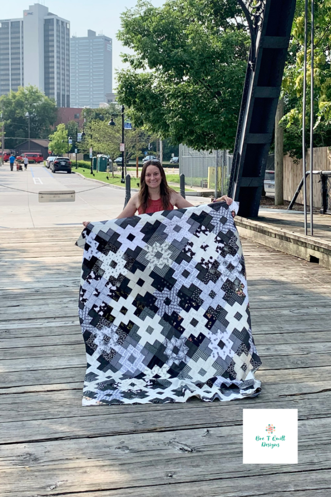 quilter holding her black and white scrap clover fields quilt top.