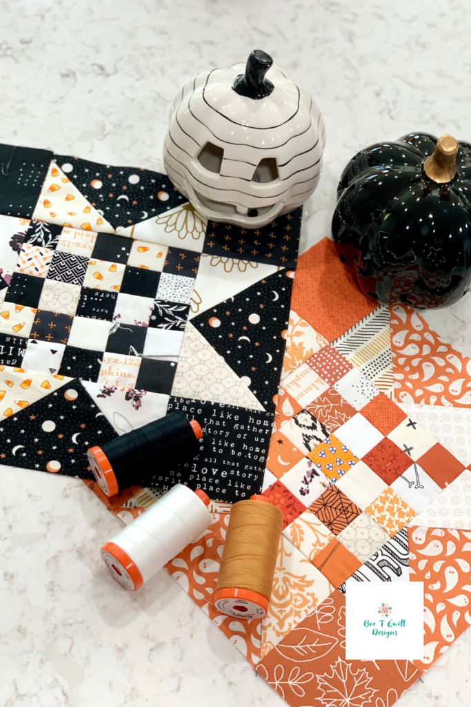 Checked star blocks in orange and black staged with aurifil thread spools and ceramic pumpkins.